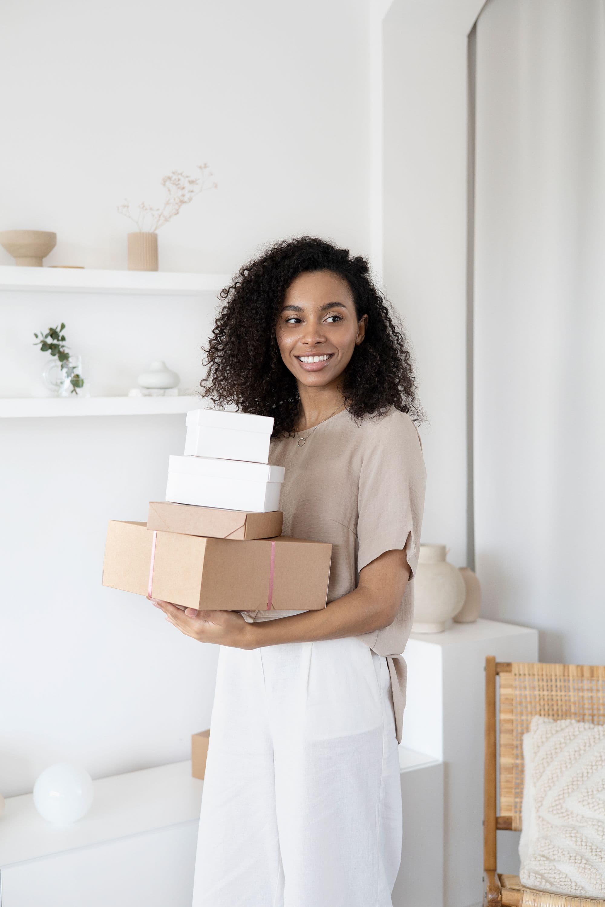A seller in a bright, tidy room holding a stack of wrapped orders ready to go out